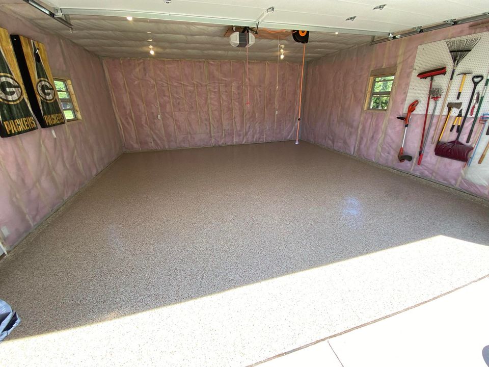 A clean garage with pink insulation walls, organized tools on one side, and Green Bay Packers banners hanging from the opposite wall.