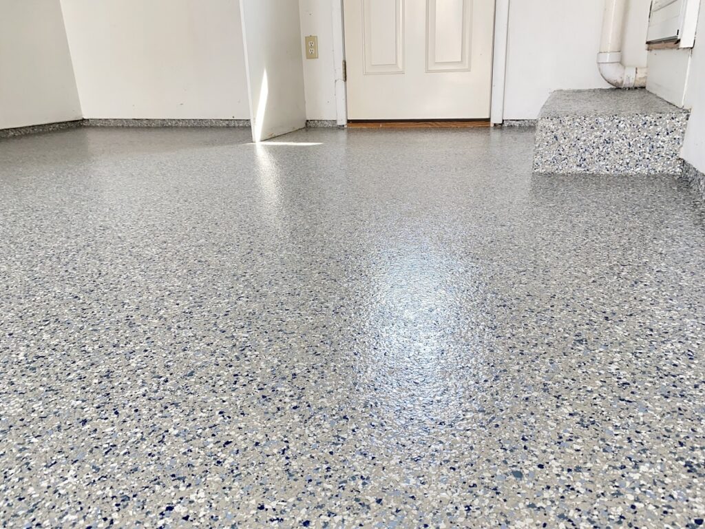Polished speckled garage floor with a step leading to a door, featuring a clean, bright interior and simple design details.